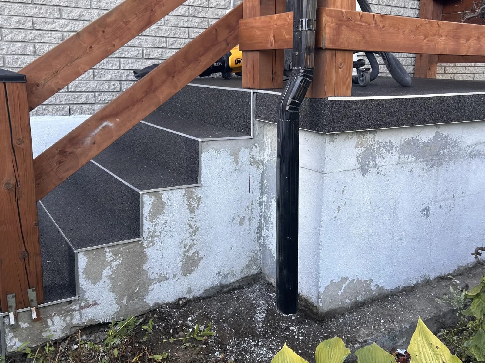 Flancs de perron en béton peint en blanc, peinture écaillée par plaques, à côté des marches