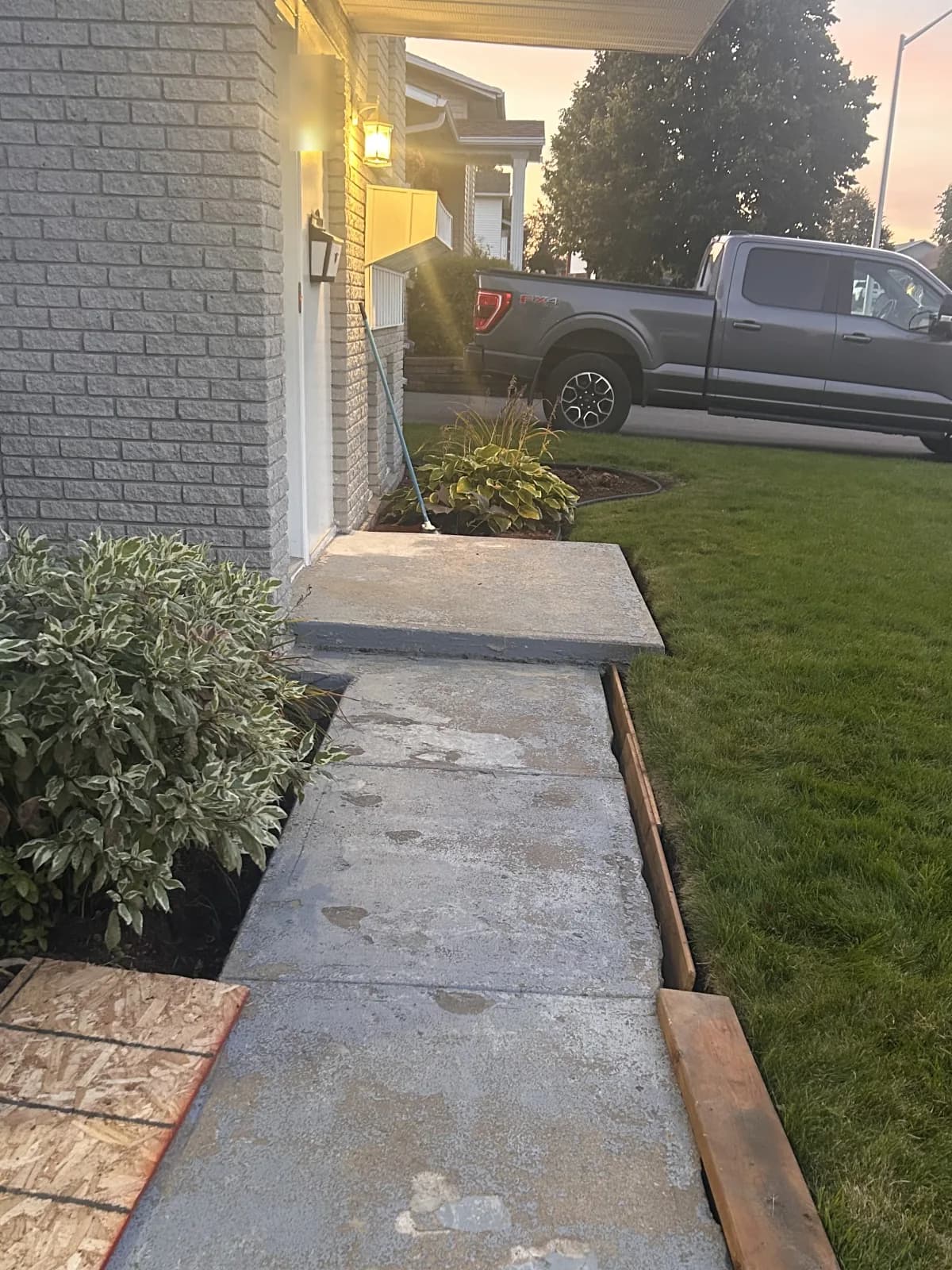 Allée de béton peinte en gris, peinture usée par plaques, vue depuis le perron