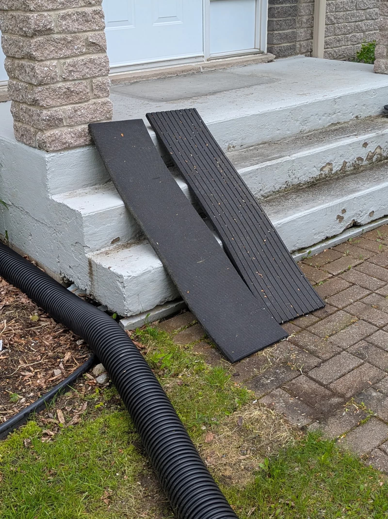 Perron de béton peint, peinture écaillée, deux tapis de caoutchouc posés sur les marches